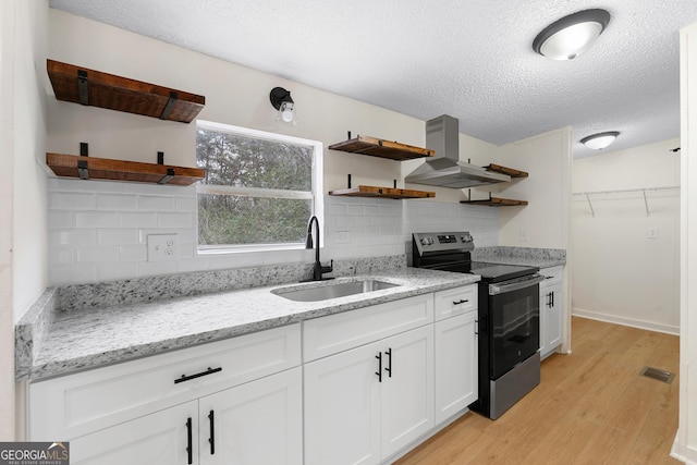 kitchen with wall chimney exhaust hood, sink, stainless steel range with electric cooktop, white cabinetry, and light stone countertops