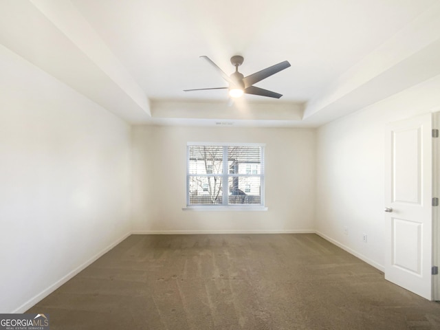 carpeted spare room featuring a tray ceiling and ceiling fan