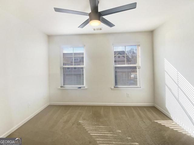 carpeted spare room featuring plenty of natural light and ceiling fan