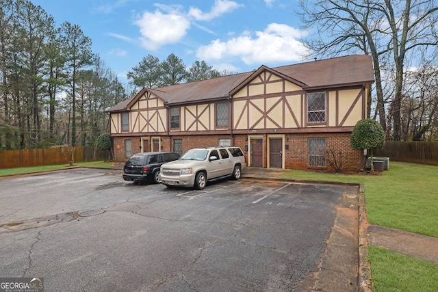 english style home with central AC unit and a front yard