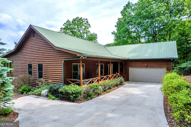 log-style house featuring a garage, covered porch, driveway, and metal roof