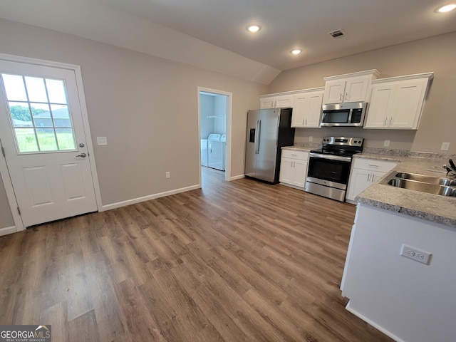 kitchen with lofted ceiling, sink, stainless steel appliances, white cabinets, and separate washer and dryer