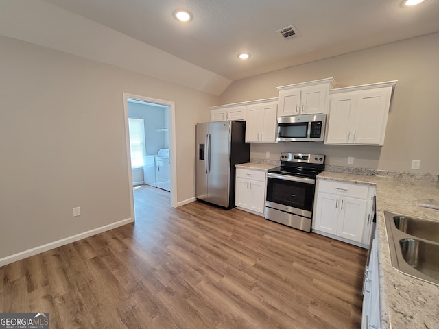 kitchen with stainless steel appliances, white cabinetry, separate washer and dryer, and vaulted ceiling