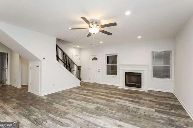 unfurnished living room featuring dark wood-type flooring and ceiling fan