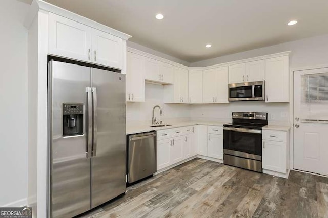 kitchen featuring stainless steel appliances, sink, hardwood / wood-style floors, and white cabinets