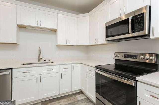 kitchen with sink, light hardwood / wood-style floors, white cabinets, and appliances with stainless steel finishes