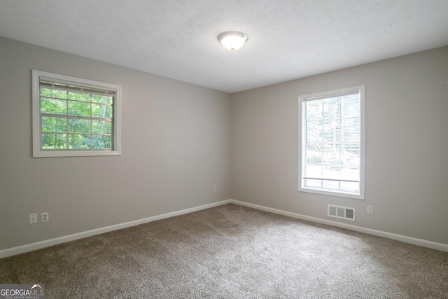 carpeted empty room with a textured ceiling