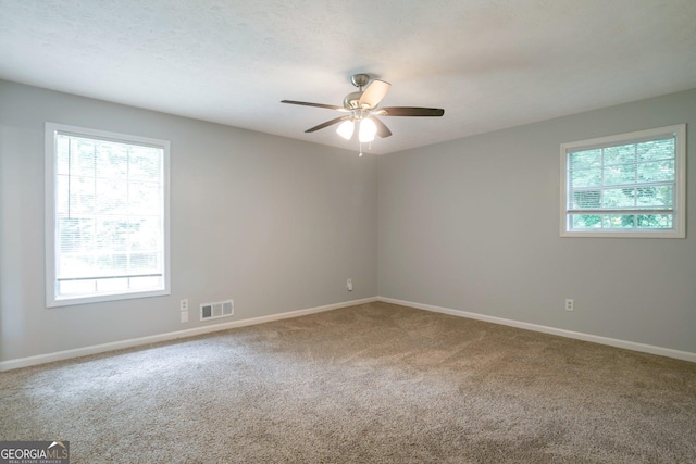 carpeted spare room featuring ceiling fan and a healthy amount of sunlight