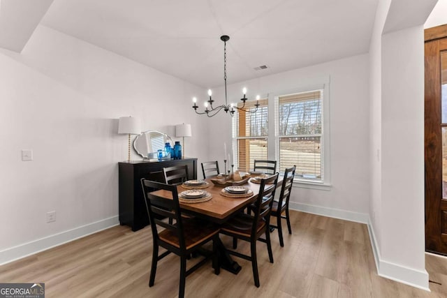 dining room with an inviting chandelier and light hardwood / wood-style flooring