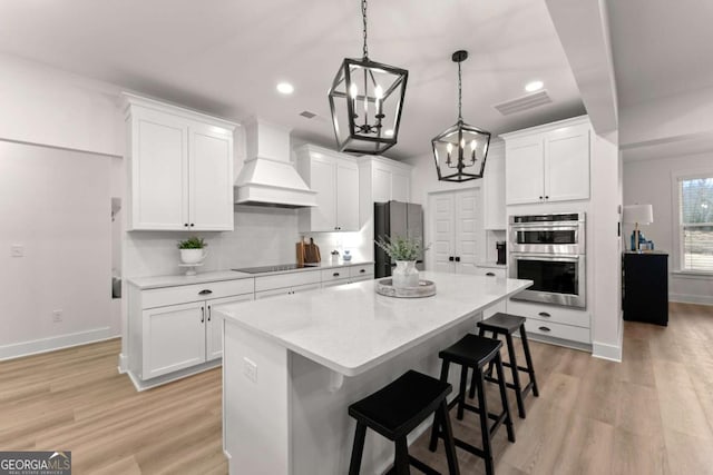 kitchen with premium range hood, appliances with stainless steel finishes, and white cabinets