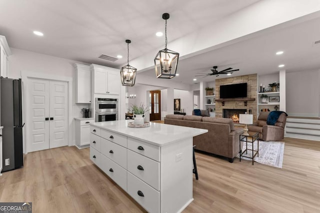 kitchen with a kitchen bar, a center island, black refrigerator, double oven, and white cabinets