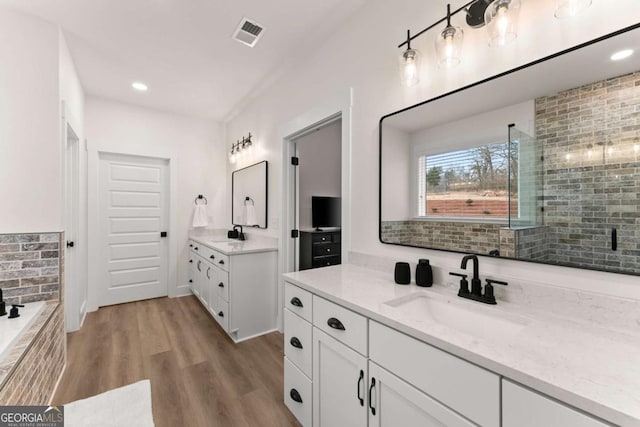 bathroom with vanity, hardwood / wood-style flooring, decorative backsplash, and walk in shower