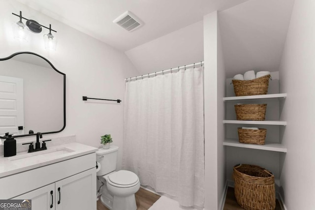 bathroom with vanity, hardwood / wood-style floors, vaulted ceiling, and toilet