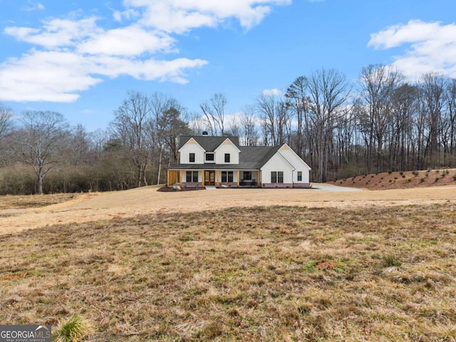 new england style home featuring a porch and a front lawn