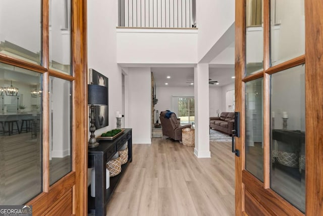 foyer with a towering ceiling, a notable chandelier, and light hardwood / wood-style floors