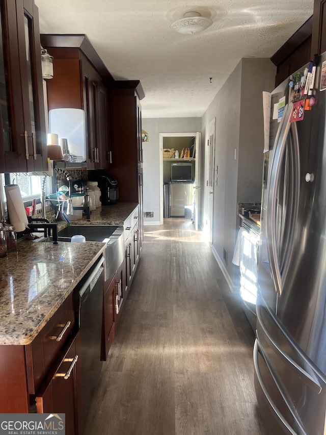 kitchen with dishwasher, dark wood-style floors, freestanding refrigerator, light stone countertops, and a textured ceiling