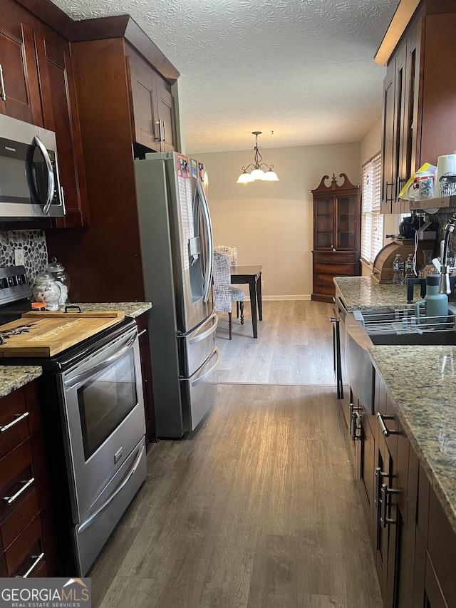 kitchen featuring appliances with stainless steel finishes, a notable chandelier, dark wood finished floors, and a textured ceiling