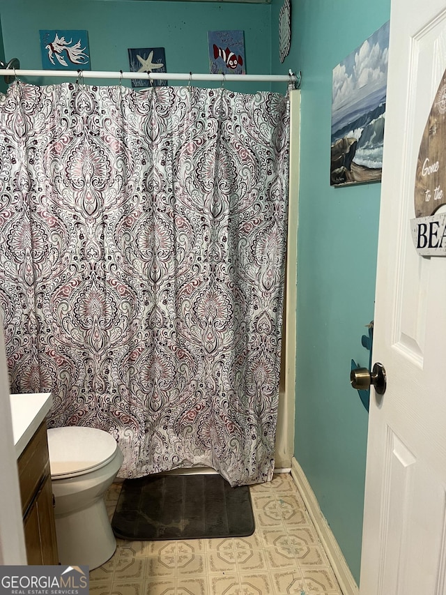 bathroom with baseboards, toilet, curtained shower, tile patterned flooring, and vanity