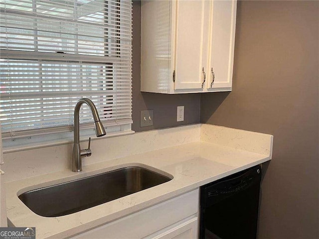 kitchen with white cabinetry, black dishwasher, sink, and light stone countertops