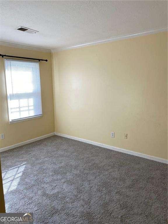 carpeted empty room with ornamental molding and a textured ceiling