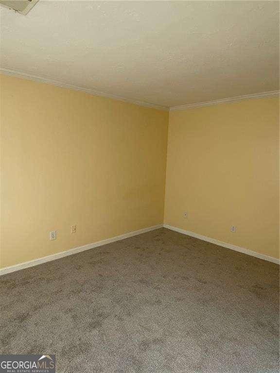 carpeted spare room featuring crown molding