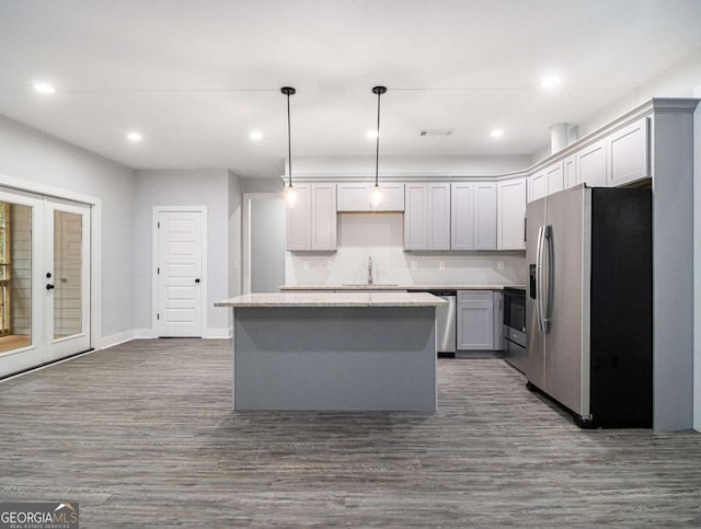 kitchen with decorative light fixtures, stainless steel appliances, dark hardwood / wood-style floors, and a kitchen island