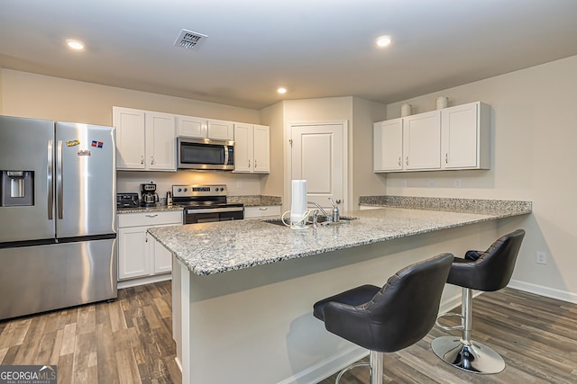 kitchen with stainless steel appliances, kitchen peninsula, and white cabinets