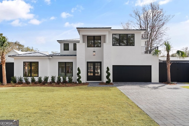 view of front of home featuring a garage, french doors, and a front lawn