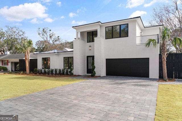 contemporary home featuring a garage, a front yard, and a balcony