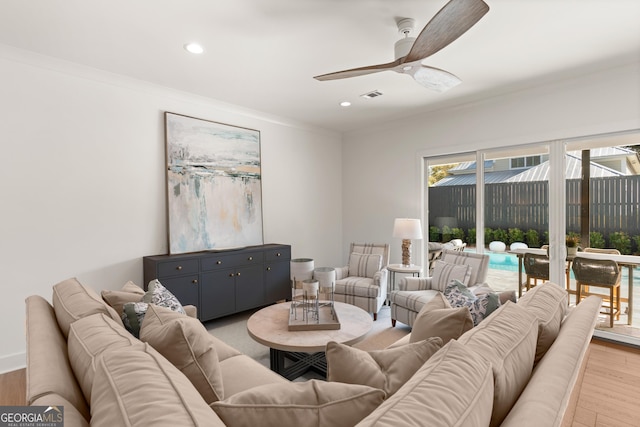 living room with light hardwood / wood-style flooring, ornamental molding, and ceiling fan