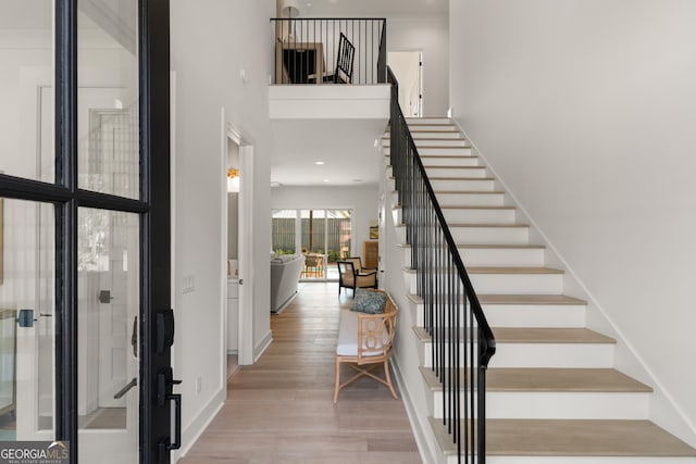 entryway with a towering ceiling, light hardwood / wood-style floors, and french doors