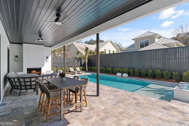 view of pool featuring ceiling fan, a fireplace, and a patio