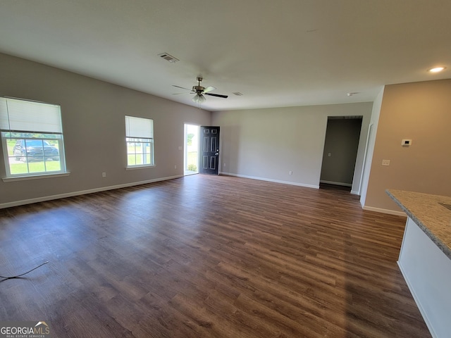 unfurnished living room featuring dark wood-type flooring and ceiling fan