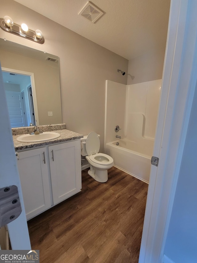 full bathroom with toilet, a textured ceiling, shower / tub combination, vanity, and hardwood / wood-style floors