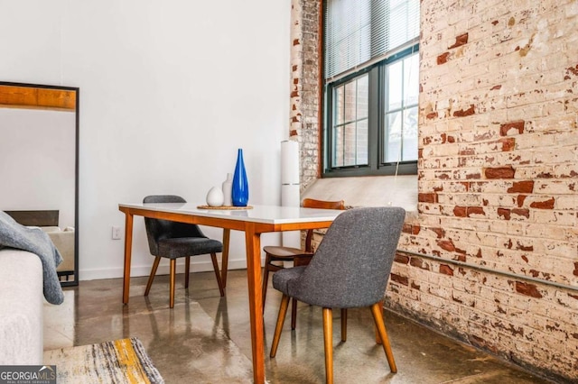 dining room with brick wall and concrete flooring