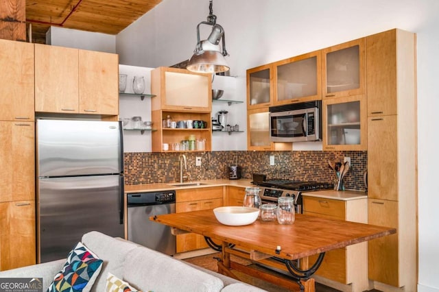 kitchen with stainless steel appliances, tasteful backsplash, sink, and decorative light fixtures