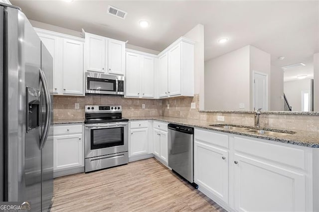 kitchen featuring white cabinetry, stainless steel appliances, sink, and stone counters