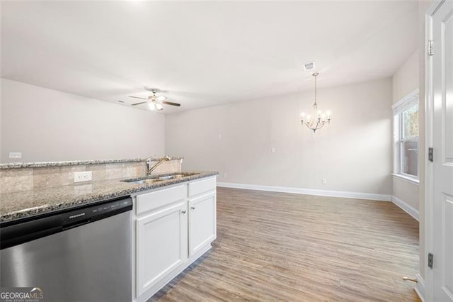 kitchen featuring pendant lighting, sink, light stone countertops, white cabinets, and stainless steel dishwasher