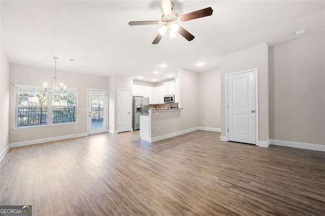 unfurnished living room with hardwood / wood-style flooring and ceiling fan with notable chandelier