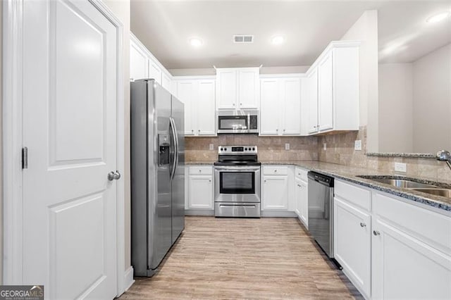 kitchen with white cabinetry, appliances with stainless steel finishes, stone countertops, and decorative backsplash