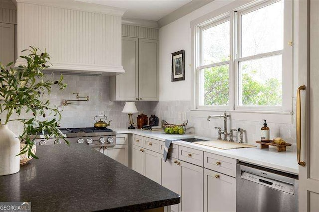 kitchen with stove, sink, stainless steel dishwasher, and decorative backsplash