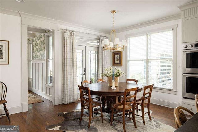 dining space featuring an inviting chandelier, crown molding, and dark wood-type flooring