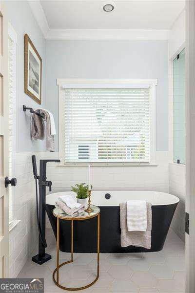 bathroom with ornamental molding, tile walls, and a bathtub