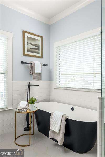 bathroom featuring crown molding, a washtub, and tile walls