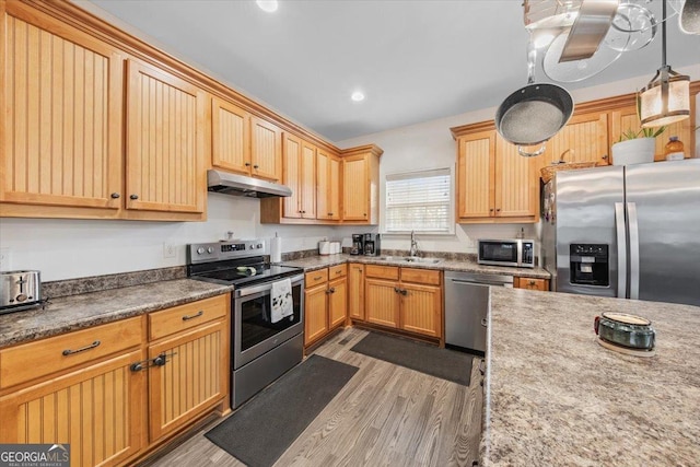 kitchen featuring appliances with stainless steel finishes, sink, dark wood-type flooring, and pendant lighting