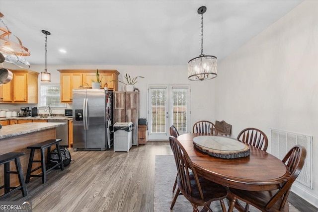 dining room featuring a wealth of natural light, sink, hardwood / wood-style floors, and a chandelier