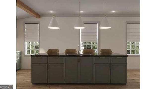 kitchen with a sink, light wood-type flooring, dark countertops, and pendant lighting