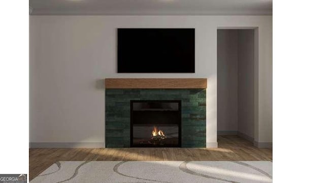 interior details featuring baseboards, wood finished floors, and a tile fireplace