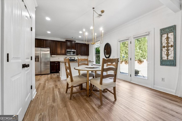 dining space with an inviting chandelier, sink, crown molding, and light hardwood / wood-style flooring