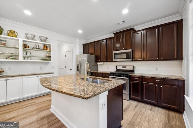 kitchen with sink, appliances with stainless steel finishes, light hardwood / wood-style floors, light stone countertops, and an island with sink